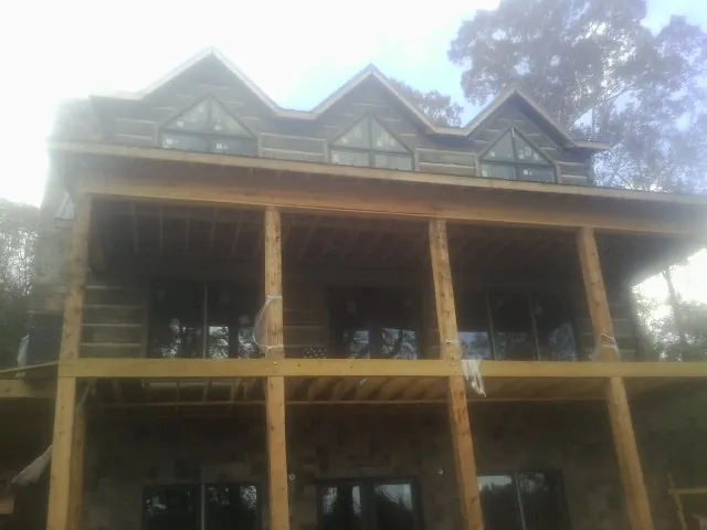 Dormers and porch framing on a large log home under construction — Roof Coating work by our crew in Plummer