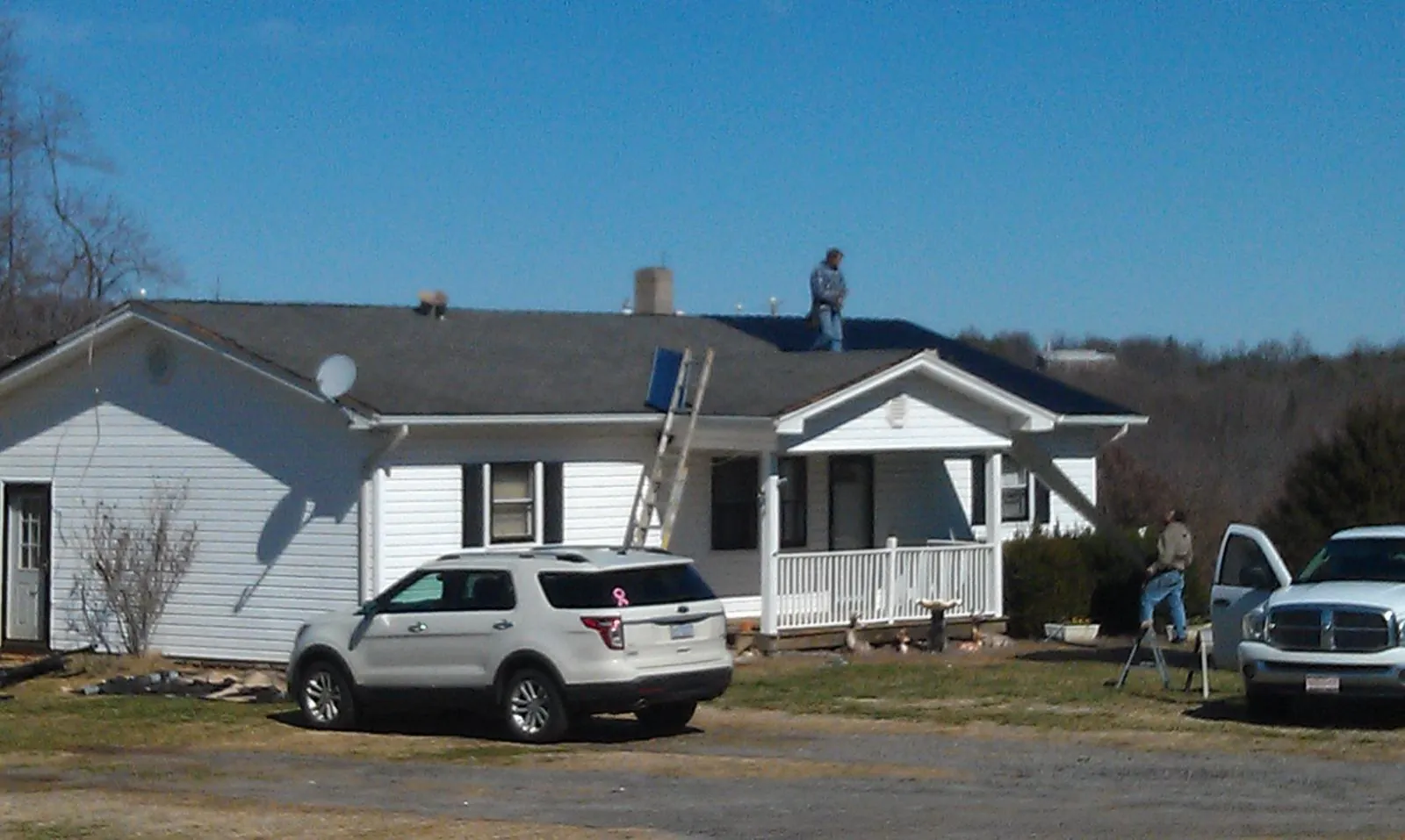 Roofers stripping shingles from a white ranch house roof in Plummer