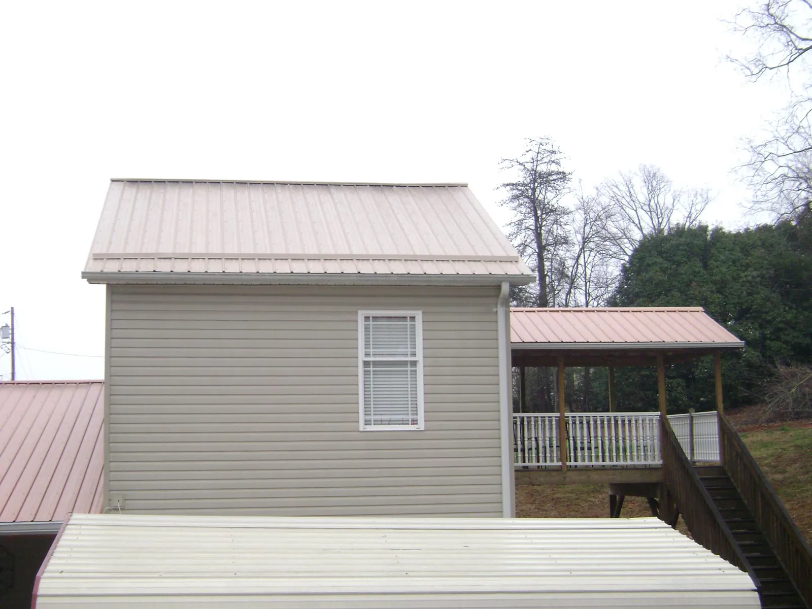 Tan metal roofs on a two story addition and attached porch, from a Roof Replacement job in Plummer